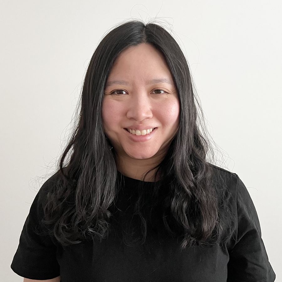 Janitta Wong, smiling, in a black top against a pale wall